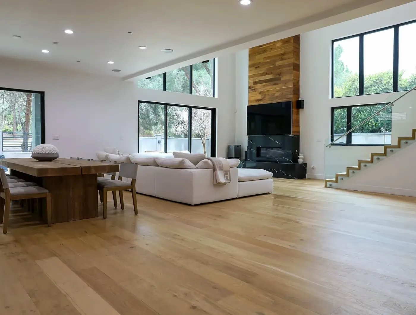 Modern living room with wood floors, white sectional sofa and floor-to-ceiling windows